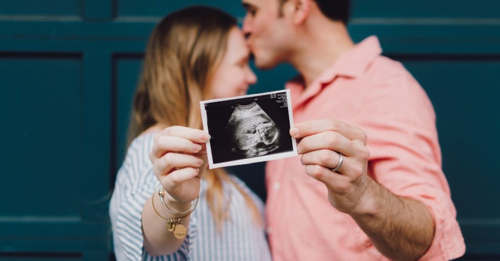 married couple showing off a picture of an unborn baby. Plan A Baby Shower On A Budget